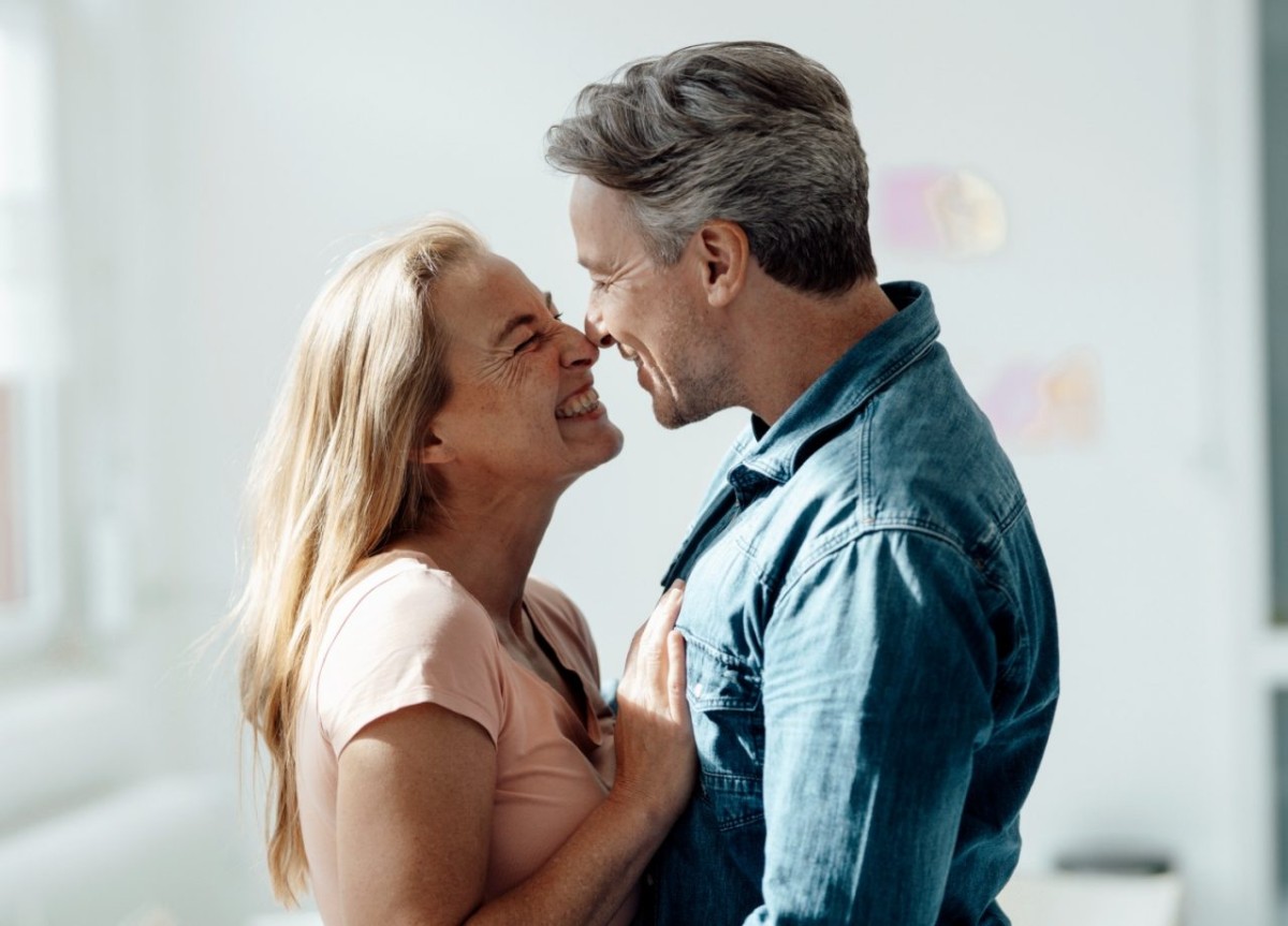 Un couple mature souriant tendrement l’un vers l’autre, incarnant l’amour et la complicité après 24 ans de mariage pour célébrer leurs noces de satin.